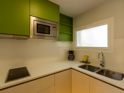 a kitchen with green cabinets and a sink and a microwave at Apartamentos Sunway Arizona in Sitges