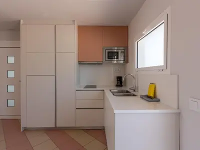 a kitchen with white cabinets and a sink and a window at Apartamentos Sunway Arizona in Sitges