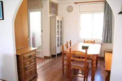 a dining room with a table and chairs and two windows at Apartamento con Licencia en Sitges in Sitges