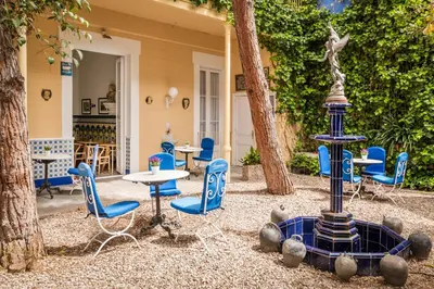 a patio with a fountain and chairs and tables at Hotel Medium Renaixença in Sitges