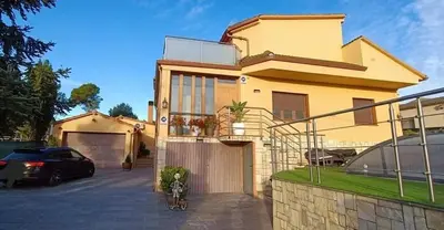 a yellow house with a car parked in a driveway at Raco de Lis in La Torre de Claramunt