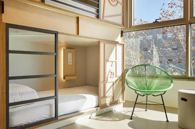a room with a bed and a chair in front of a window at Unite Hostel Barcelona in Barcelona