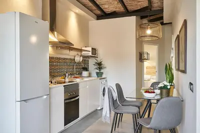 a kitchen with white appliances and a table with chairs at AinB Eixample-Miro Apartments in Barcelona