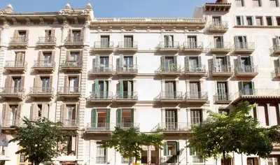 a large white building with balconies and trees in front of it at HoHomes - Centric Design Apartment in Barcelona