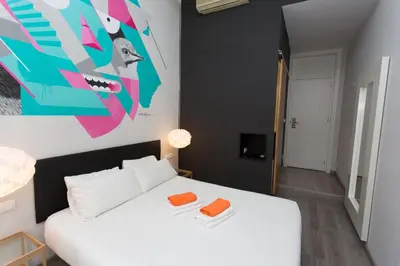 a bedroom with a white bed and a painting on the wall at ZOOROOMS Boutique Guesthouse in Barcelona