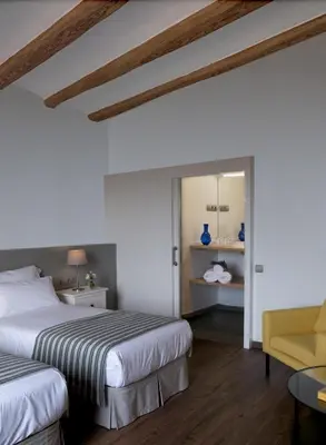 a bedroom with two beds and a yellow chair at La Frasera Alojamiento Rural in Vacarisas