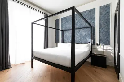 a bedroom with a black canopy bed with white sheets at Maldà Singular Hotel in Barcelona