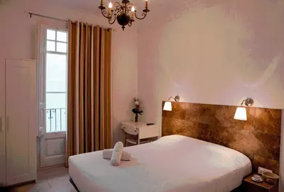 a bedroom with a large white bed and a window at Hostal Martinval in Barcelona
