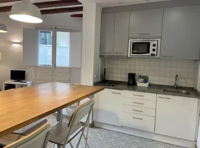 a kitchen with white cabinets and a wooden table at Ripoll Apartments in Barcelona