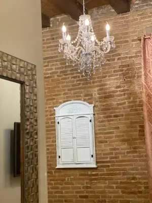 a chandelier and a white cabinet on a brick wall at Hostal Orleans in Barcelona