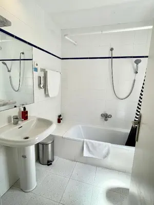 a white bathroom with a tub and a sink at Madison Rooms in Sitges
