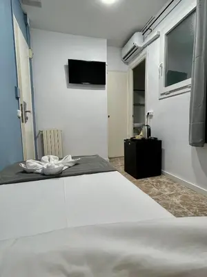 a bedroom with a bed and a tv on the wall at Madison Rooms in Sitges