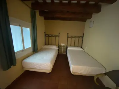 two beds in a room with two windows at Hotel Peninsular in Barcelona