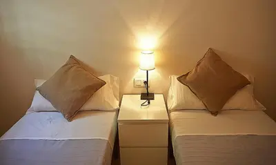 a bedroom with two beds and a lamp on a night stand at Alguera Apartments Sant Andreu in Barcelona