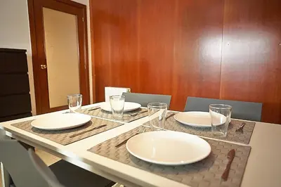 a table with white plates and glasses on it at Alguera Apartments Sant Andreu in Barcelona