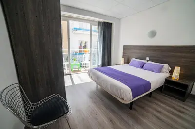 a bedroom with a bed and a chair and a window at Apartaments Atzavara in Calella
