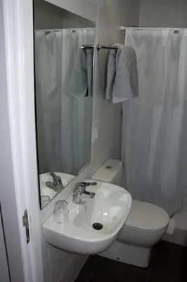 a bathroom with a sink and a toilet and a mirror at Hostalin Barcelona Diputacion in Barcelona