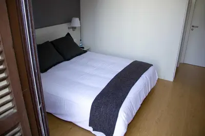 a bedroom with a bed with white sheets and black pillows at Hostalin Barcelona Diputacion in Barcelona