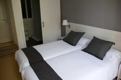 a bedroom with two beds with white sheets and gray pillows at Hostalin Barcelona Diputacion in Barcelona