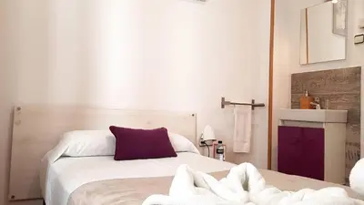 a bedroom with a white bed with a purple pillow at Hostal la Palmera in Barcelona