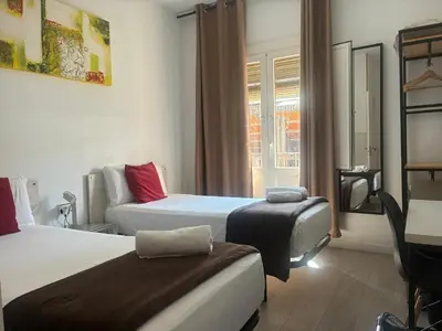 a hotel room with two beds and a chair at Hostal la Palmera in Barcelona