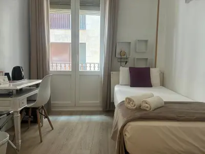 a bedroom with two beds and a desk and a window at Hostal la Palmera in Barcelona