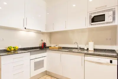 a white kitchen with white cabinets and a microwave at Novus Homes Barcelona Gracia in Barcelona