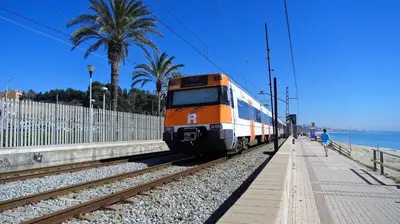 an orange and white train on the tracks near the beach at CASA FLAMINGO in Masnou