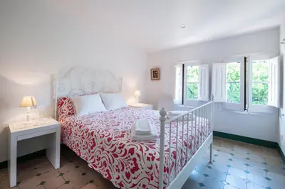 a white bedroom with a bed with a red and white bedspread at Apartament Can Mateu-Gran Terraza in Vilassar de Mar
