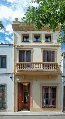 a white house with a red door and a balcony at Apartament Can Mateu-Gran Terraza in Vilassar de Mar