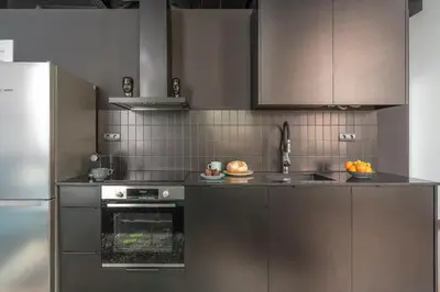 a kitchen with stainless steel appliances and brown cabinets at TSA La Rosa in Barcelona
