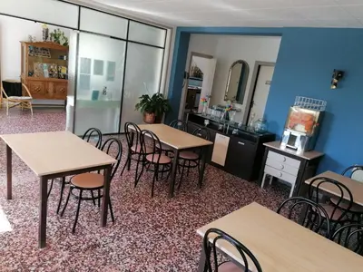 a room with tables and chairs and a kitchen at Hostal Santa Gemma in Sant Vicenç de Montalt
