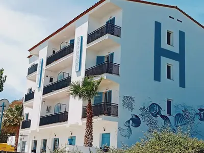 a white building with a palm tree in front of it at Hostal Santa Gemma in Sant Vicenç de Montalt