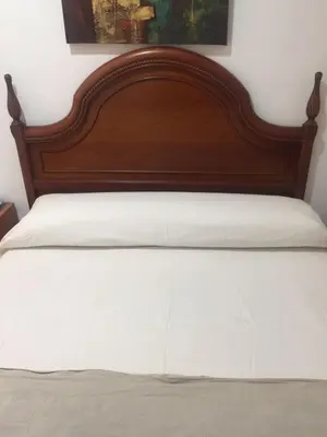 a bed with a wooden headboard and white sheets at Pensión Teruel in Barcelona