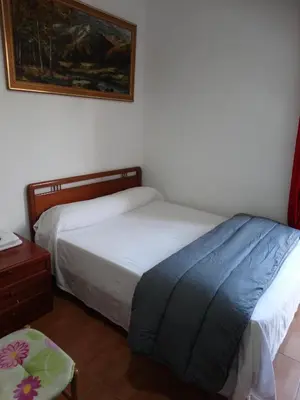 a bedroom with two beds and a table and a picture at Pensión Teruel in Barcelona