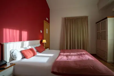 a bedroom with a large white bed with red walls at Hotel & Spa Golden Barcelona in Vallromanas