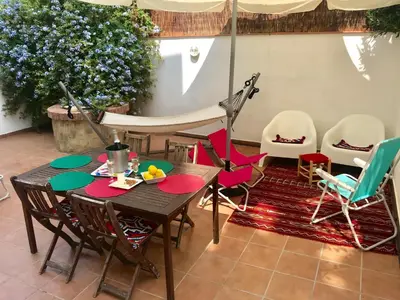 a patio with a wooden table and colorful chairs at Seaside Apartment in Sitges Steps from Beaches with private Patio in Sitges