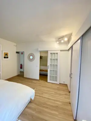 a bedroom with a white bed and a wooden floor at Seaside Apartment in Sitges Steps from Beaches with private Patio in Sitges