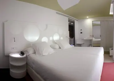 a white bedroom with a white bed and a bathroom at Room Mate Pau, Barcelona in Barcelona
