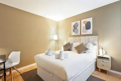 a bedroom with a white bed and a desk at Ola Living Diagonal Apartments in Barcelona