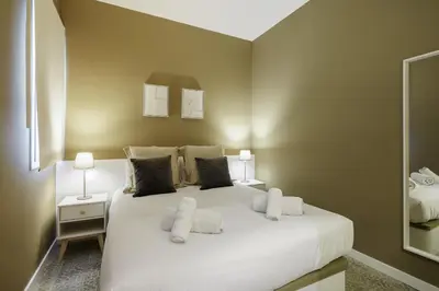 a bedroom with a large white bed with two lamps at Ola Living Diagonal Apartments in Barcelona