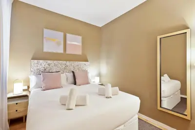 a bedroom with a large white bed and a mirror at Ola Living Diagonal Apartments in Barcelona