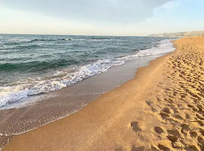 a beach with footprints in the sand and water at Siroco by Seaside Homes in Castelldefels