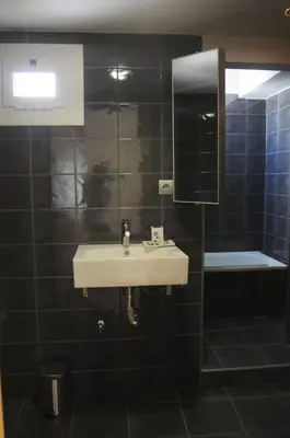 a black tiled bathroom with a sink and a mirror at Hotel Ibiza in Sitges