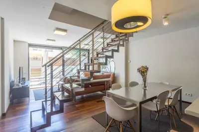 a living room with a dining room table and stairs at My Space Barcelona Pool Garden Apartments in Barcelona