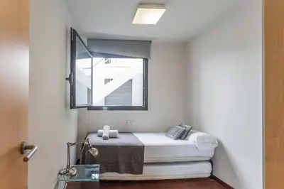 a small bedroom with a bed and a mirror at My Space Barcelona Pool Garden Apartments in Barcelona