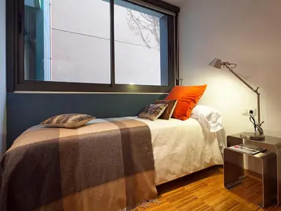 a bedroom with a bed with an orange pillow and a window at My Space Barcelona Park Güell Apartments in Barcelona