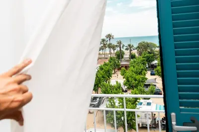 a person looking out of a window at the ocean at Bellsol Rooms in Pineda de Mar