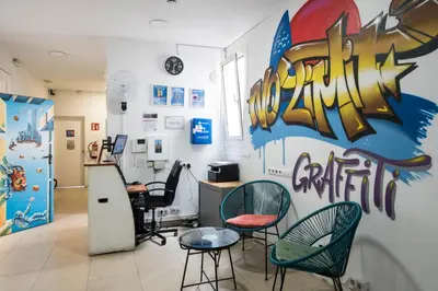 a room with chairs and a counter with graffiti on the wall at No Limit Hostel Graffiti in Barcelona
