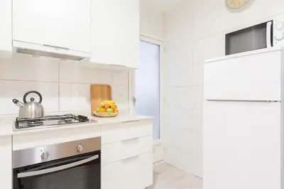 a white kitchen with a stove and a sink at Novus Homes Barcelona Collblanc in Hospitalet de Llobregat